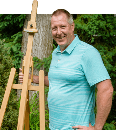 Roger Holliss standing beside easel